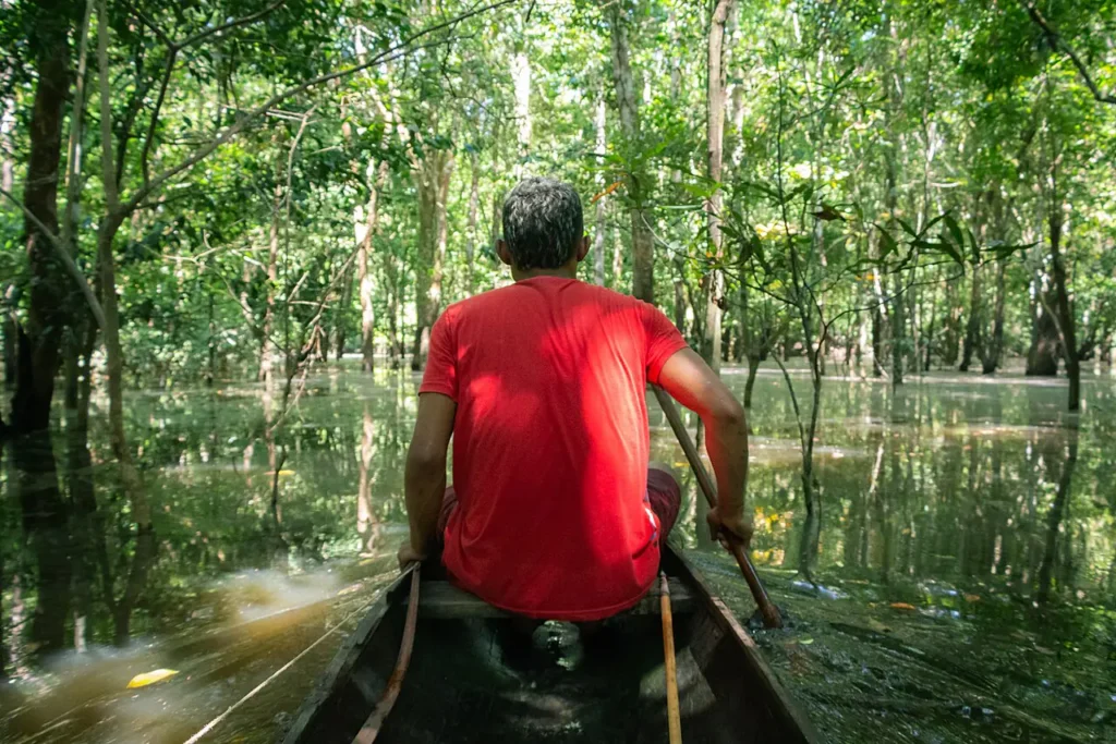 Homem rema canoa em área de floresta alagada no rio Juruá
